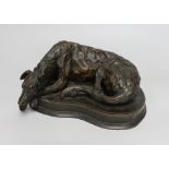 A bronzed resin model of a recumbent dog, 25cm long