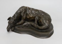 A bronzed resin model of a recumbent dog, 25cm long
