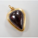 A late Victorian yellow metal (stamped 18) and cabochon garnet set heart shaped pendant, with glazed