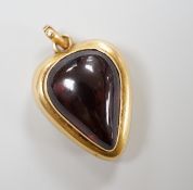 A late Victorian yellow metal (stamped 18) and cabochon garnet set heart shaped pendant, with glazed
