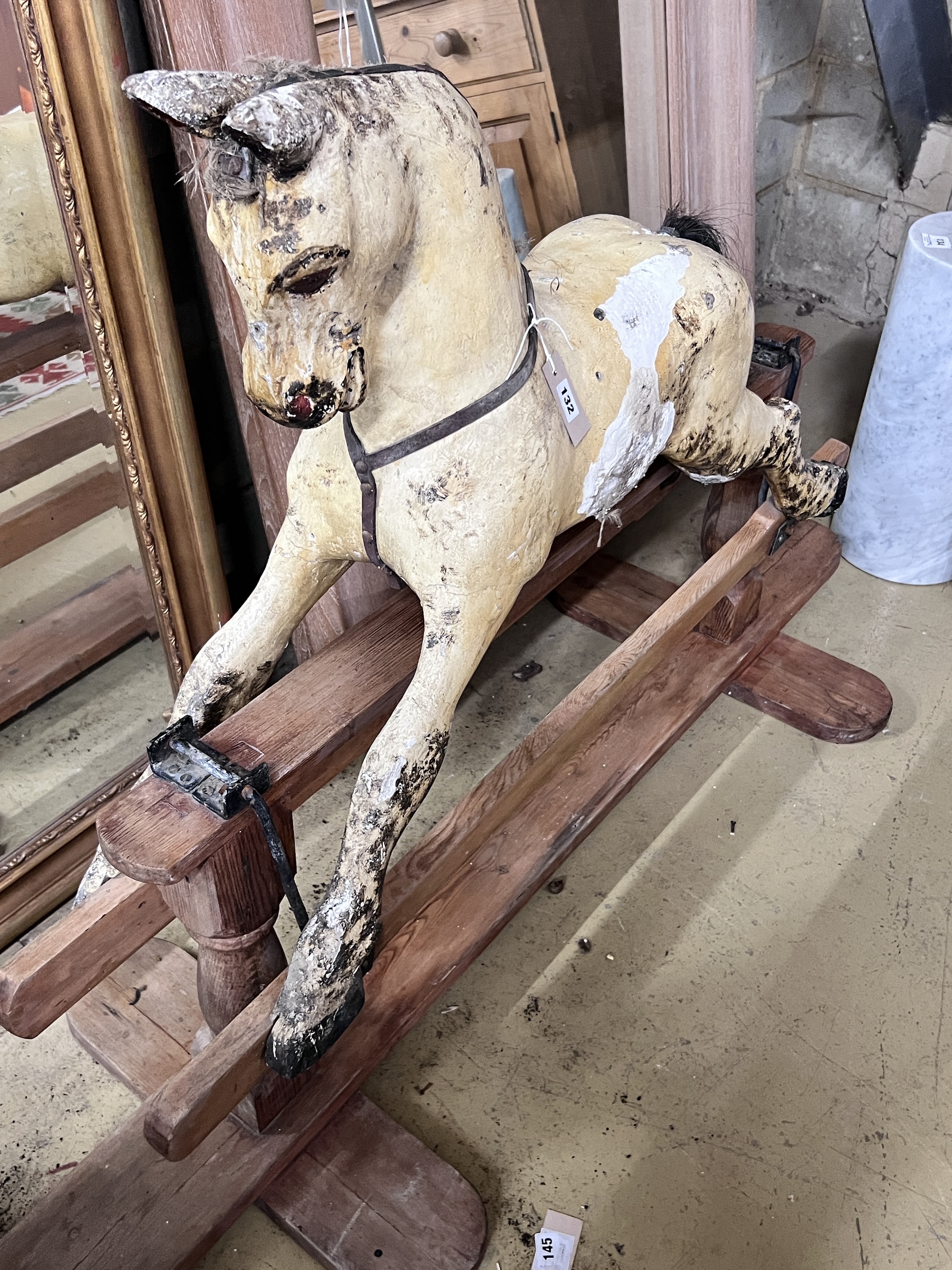An early 20th century rocking horse on pine safety frame, length 152cm, height 98cm