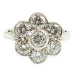 A platinum and seven stone diamond cluster set flower head ring, the millegrain set stones with an