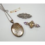 A white metal oval locket on chain, a white metal and marcasite clip brooch, a yellow metal and
