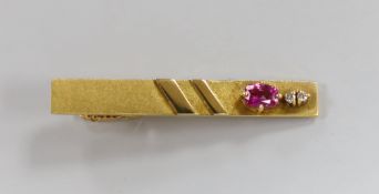 A modern 18k, ruby and diamond set three stone tie clip, 47mm, gross weight 7.7 grams.
