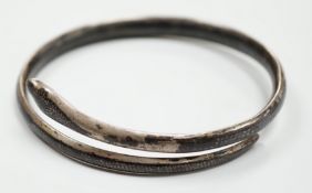 A white metal and niello serpent bangle, decorated with scene of a camel train.