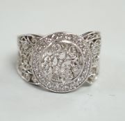 A pierced white metal and diamond chip set diamond ring, with scrolling decoration, size Q/R,