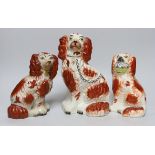Three Victorian Staffordshire pottery dogs, one holding a basket of flowers from its mouth, the