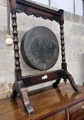 An early 20th century oak dinner gong with striker, width 68cm, height 99cm
