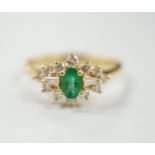 A modern 18ct gold, single stone oval cut emerald and round and trapeze cut diamond set cluster