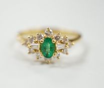 A modern 18ct gold, single stone oval cut emerald and round and trapeze cut diamond set cluster