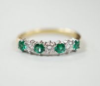 A modern 18ct gold, four stone emerald and three stone diamond set half hoop ring, size M, gross