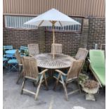 A weathered teak circular garden table, diameter 153cm, height 74cm together with six folding