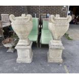 A pair of reconstituted stone garden urns on plinths, height 130cm