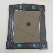 A Miller Brothers Art Nouveau embossed pewter mirror with cabochon turquoise enamel bosses, 48cm