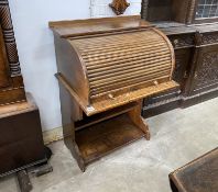 An early 20th century oval tambour roll top desk, combined bookcase, width 75cm, depth 53cm,