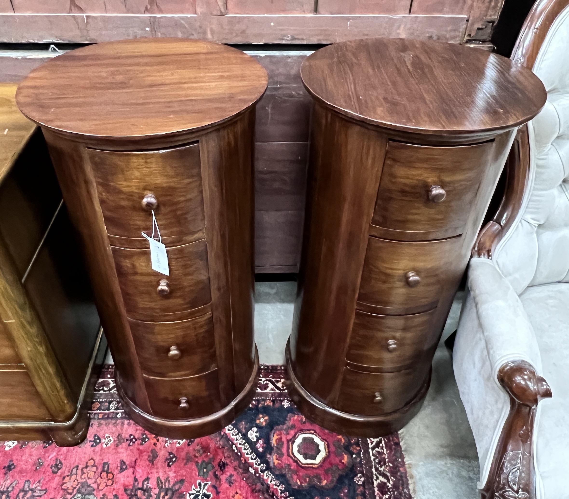 A pair of reproduction mahogany cylindrical bedside cupboards, each fitted four small drawers,