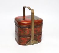 A Japanese red lacquered two section container with brass handle, 21cm high