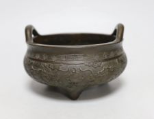 A Chinese twin handled bronze tripod censer, ding, Xuande mark, 19th century, decorated in relief