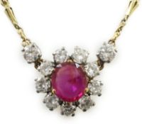 A modern 9ct gold, single stone oval cut ruby and eleven stone round cut diamond cluster set pendant