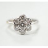 A modern 18ct white gold and seven stone diamond set flower head cluster ring, size O, gross