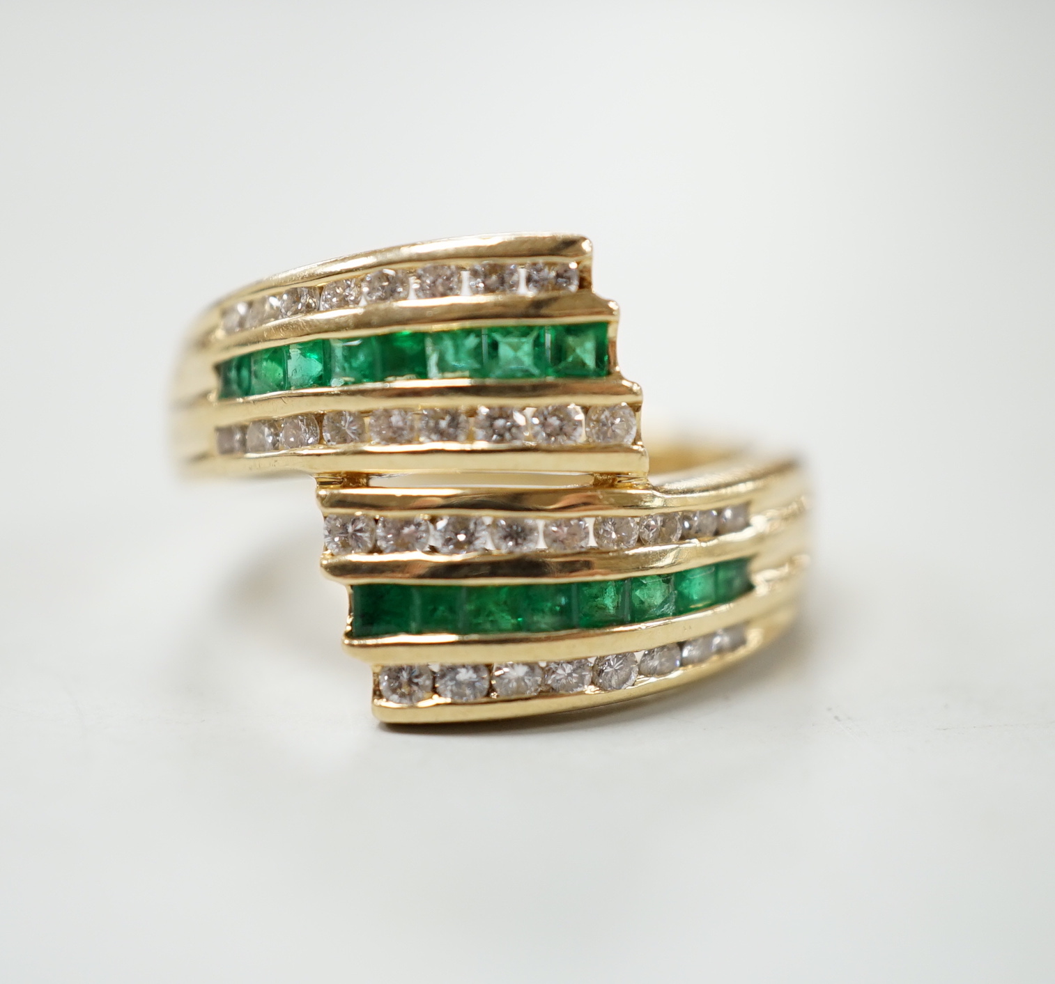 A modern 14k yellow metal, emerald and diamond chip set triple row crossover ring, size O, gross