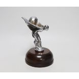 A chromium Spirit of Ecstasy car mascot, raised on a circular wood base, 19cm high