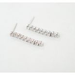 A modern pair of white metal and nine stone diamond set line drop earrings, with 925 butterflies,