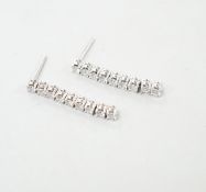A modern pair of white metal and nine stone diamond set line drop earrings, with 925 butterflies,