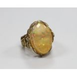 A yellow metal and oval jelly? opal set dress ring, with rustic foliate shank and setting, size L,