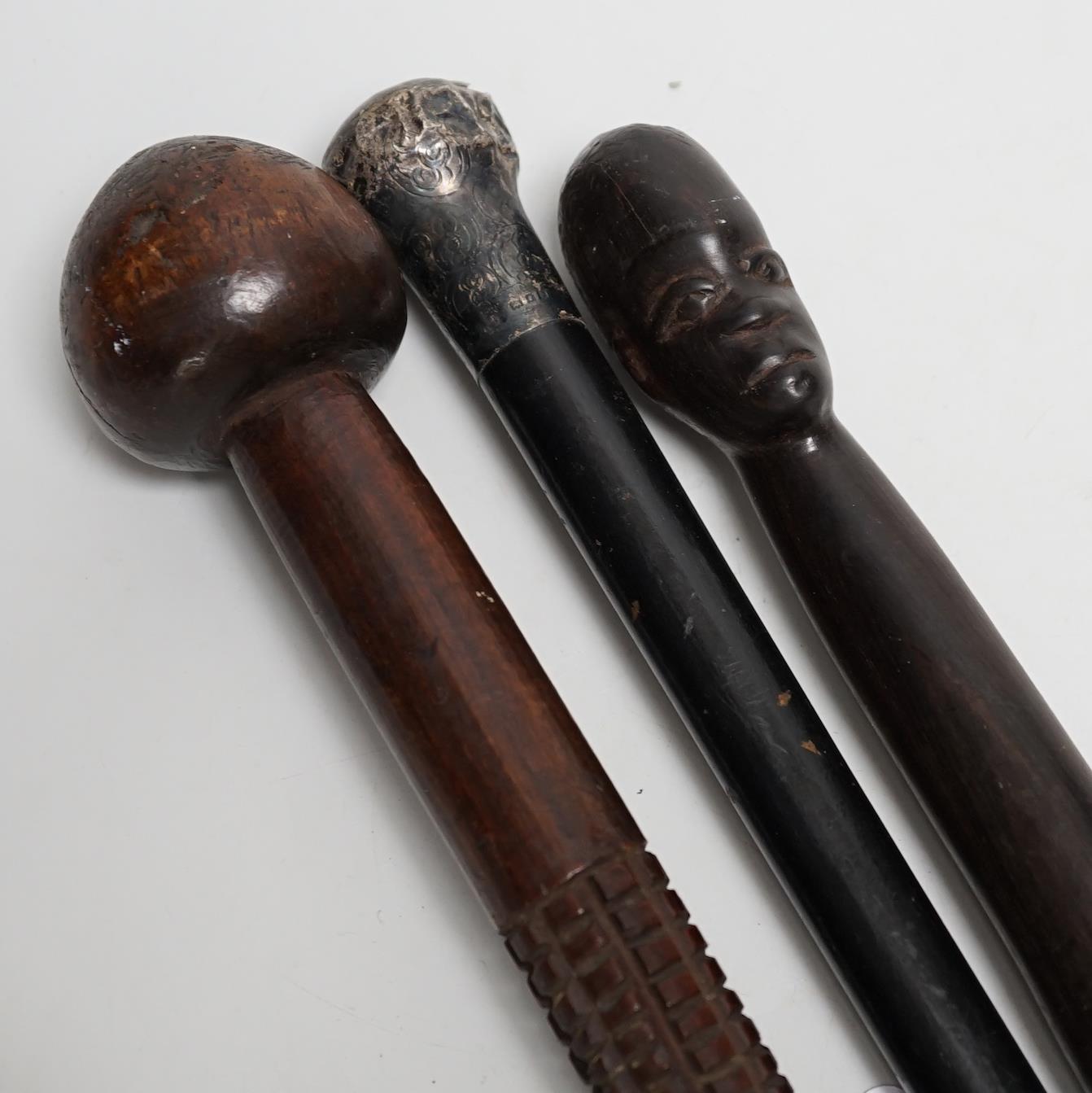 A silver topped walking cane and two African carved wood canes