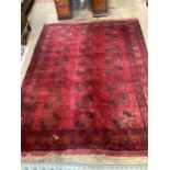 A Bokhara red ground carpet, worn and holed, 286 x 214cm