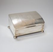 A George V engine turned silver cigarette box, of unusual sloping lidded form, with pad feet,