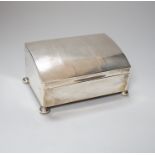 A George V engine turned silver cigarette box, of unusual sloping lidded form, with pad feet,