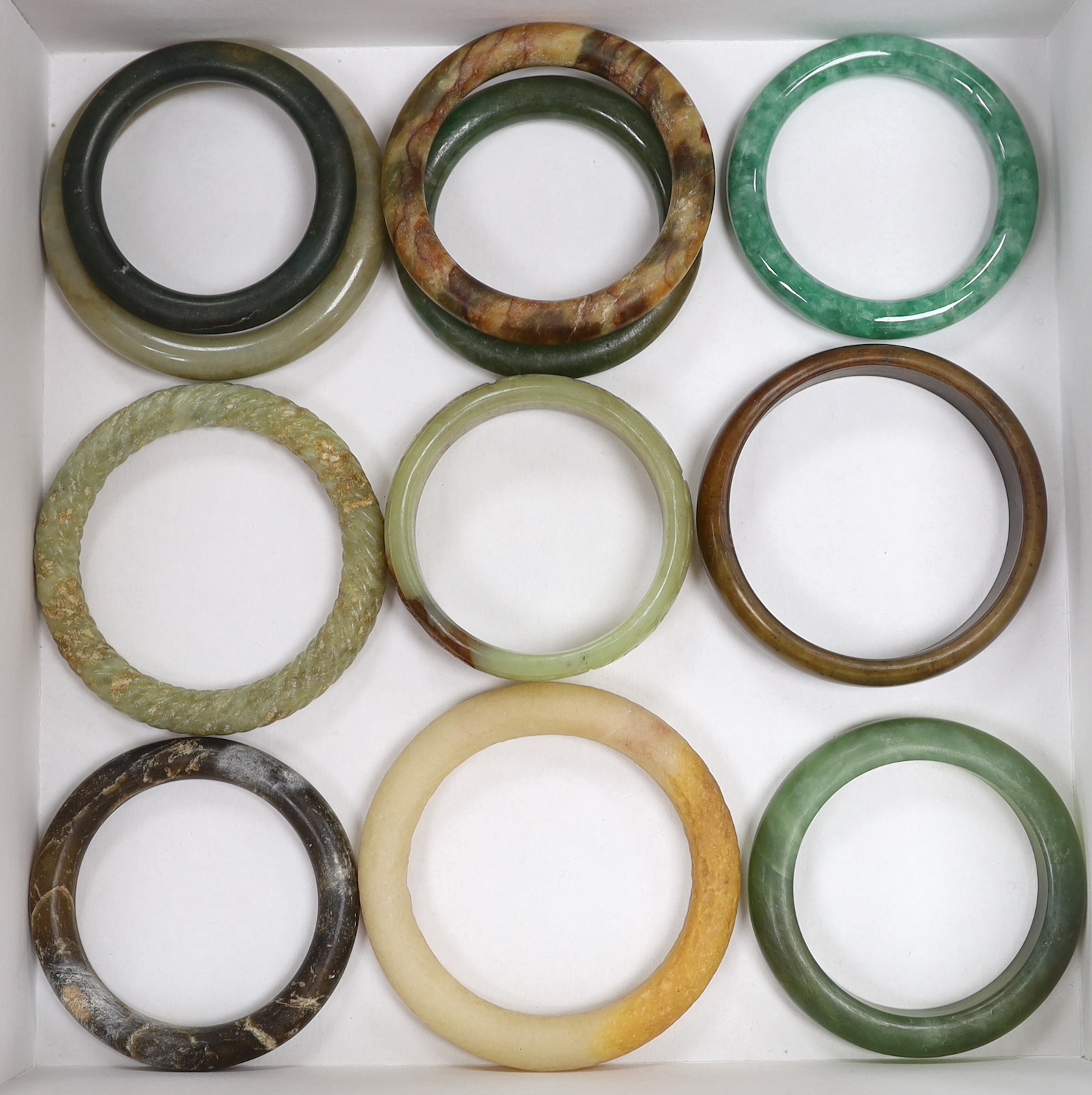 Eleven Chinese jade or hardstone bangles, largest 9cm