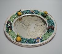 A circular earthenware mirror, possibly by Della Robbia Pottery of Liverpool, decorated with foliage