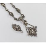 An ornate white metal and paste pendant necklace, with similar drop earrings