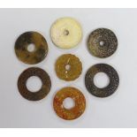 Seven Chinese jade or hardstone bi discs with carved decoration, the largest 5cm in diameter