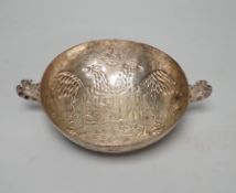 An antique continental white metal twin handled dish, embossed with a crest and double headed eagle,