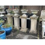 A set of four circular reconstituted stone garden planters on tall square plinths, height 134cm