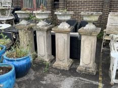 A set of four circular reconstituted stone garden planters on tall square plinths, height 134cm