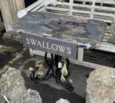 A rectangular cast iron and weathered teak garden table with a sign reading 'Swallows', width