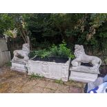 A pair of re-constituted stone models of lions standing upon rectangular plinths, fitted as