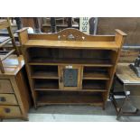 An Art Nouveau oak open bookcase, fitted with a central cupboard, the door inset with a hammered