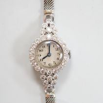 A lady's white metal and diamond set Movado manual wind cocktail watch, on a diamond set 9ct white