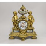 A French decorative ormolu putti mantel clock with porcelain clock face, side panels and urn