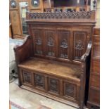 An early 20th century carved oak Gothic Revival settle with hinged box seat, width 137cm, depth