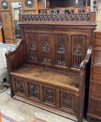 An early 20th century carved oak Gothic Revival settle with hinged box seat, width 137cm, depth