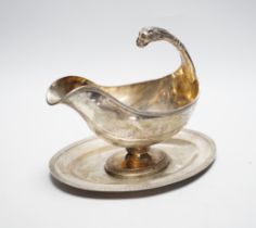 A continental white metal sauceboat on stand, with flying scroll leopard's head handle, length 23.