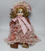 A doll with bisque face and hands, wearing a velvet dress and bonnet, 66cm high