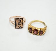 A yellow metal and three stone garnet set ring, with diamond chip spacers and a 9ct and black enamel